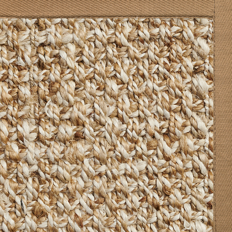 Close-up of a woven natural fiber rug with a tan fabric border, highlighting the textured, interlaced strands—perfect for comparing jute vs wool rug options or exploring jute rugs pros and cons.