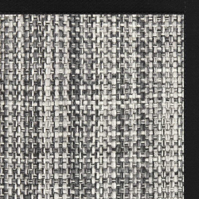 Close-up of a woven fabric in black, white, and gray tones with a thick black border on two sides, showing the texture and pattern of polypropylene in carpet materials.