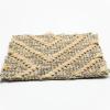 Close-up of a woven fabric with a geometric Greek key pattern in beige and light brown tones, resembling the textured surface and angular design found in polypropylene sisal look rugs.
