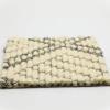 Close-up of a textured fabric with a repeating diamond pattern. The diamonds are outlined in dark gray on a cream-colored, woven background, resembling the geometric appeal of wool sisal rugs. The design creates a lattice-like appearance.