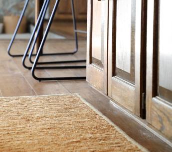 Hemp rug alongside the bottom of a oak paneled kitchen island.