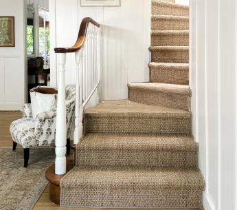 Staircase decorated with a lavish seagrass rug.